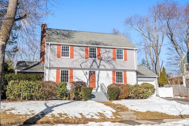 colonial inspired home with a gate, fence, and a chimney