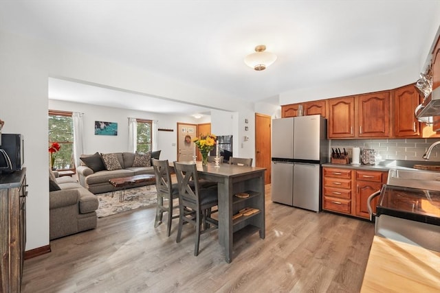 kitchen featuring sink, backsplash, stainless steel appliances, and light wood-type flooring