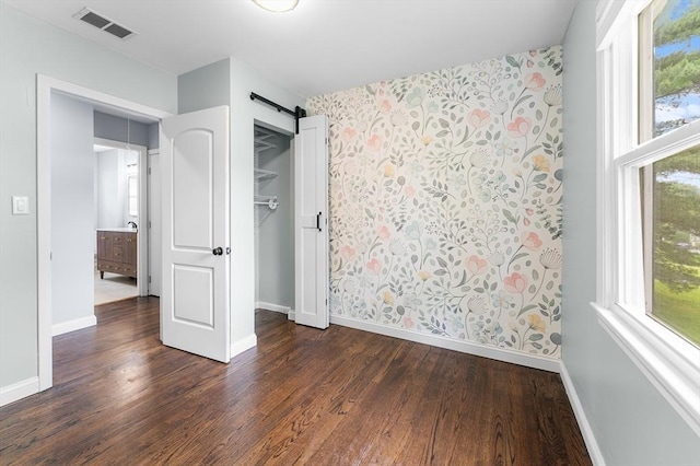26 W Park St, Franklin, MA 02038 - unfurnished bedroom featuring dark wood-style floors, wallpapered walls, a barn door, and a closet