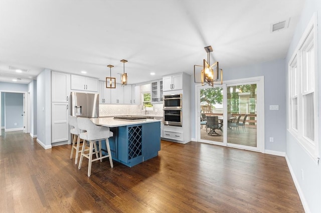 26 W Park St, Franklin, MA 02038 - kitchen featuring a chandelier, decorative backsplash, appliances with stainless steel finishes, white cabinetry, and light countertops