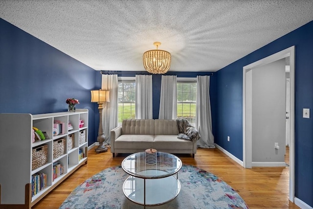 2240 Turnpike St, North Andover, MA 01845 - living room featuring a chandelier, wood finished floors, a textured ceiling, and baseboards