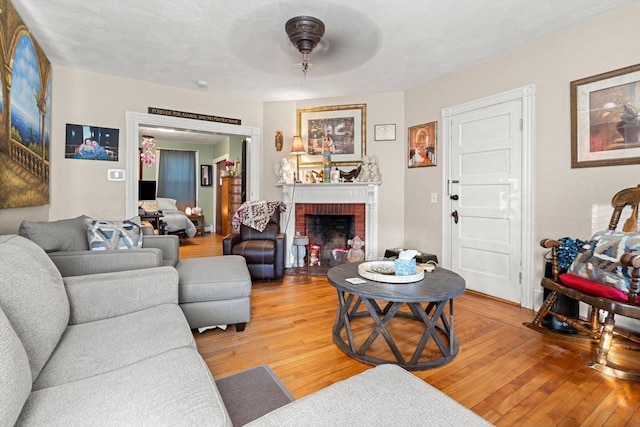 living room featuring ceiling fan, hardwood / wood-style floors, and a brick fireplace