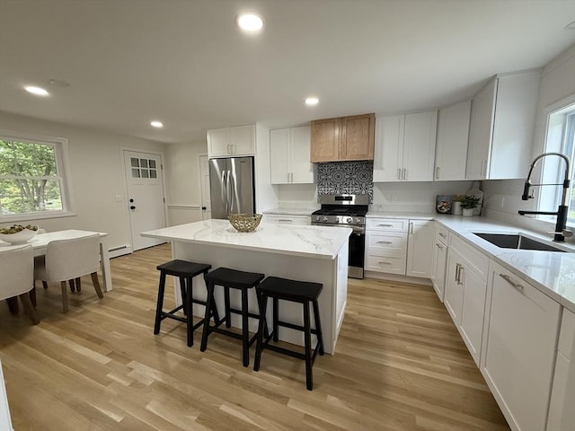 368 King St, Hanover, MA 02339 - kitchen featuring appliances with stainless steel finishes, a sink, tasteful backsplash, light stone counters, and a kitchen island