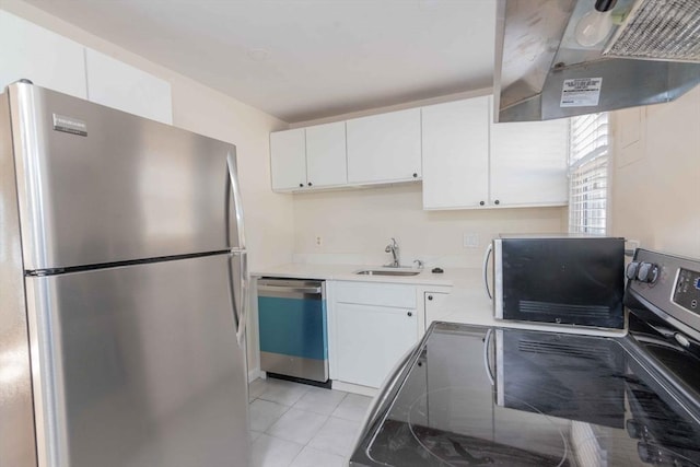 kitchen featuring dishwasher, range hood, freestanding refrigerator, white cabinetry, and a sink