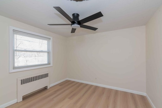 empty room featuring light wood-style floors, a ceiling fan, radiator heating unit, and baseboards