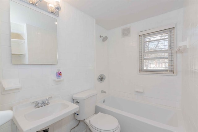 full bath with visible vents, toilet, a sink, tile walls, and washtub / shower combination