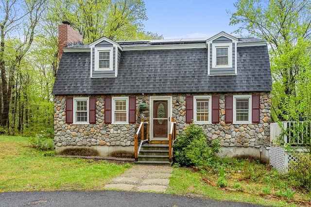 view of front of property featuring roof with shingles, a chimney, and stone siding