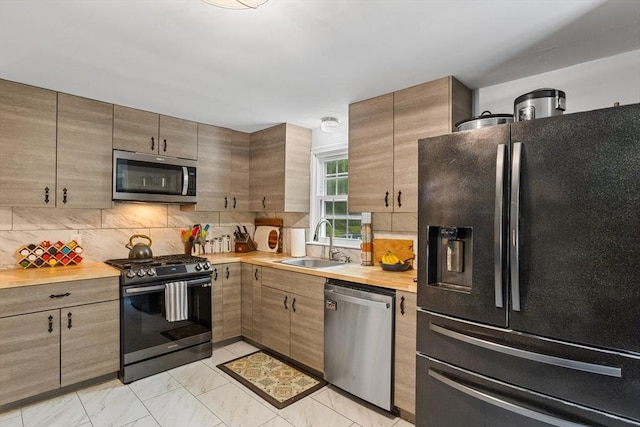 kitchen with appliances with stainless steel finishes, a sink, butcher block countertops, tasteful backsplash, and light marble finish floors