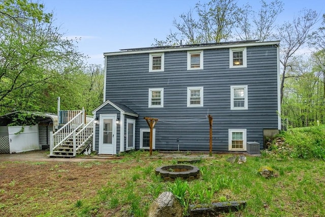 rear view of property featuring a fire pit, stairs, central AC, and a deck