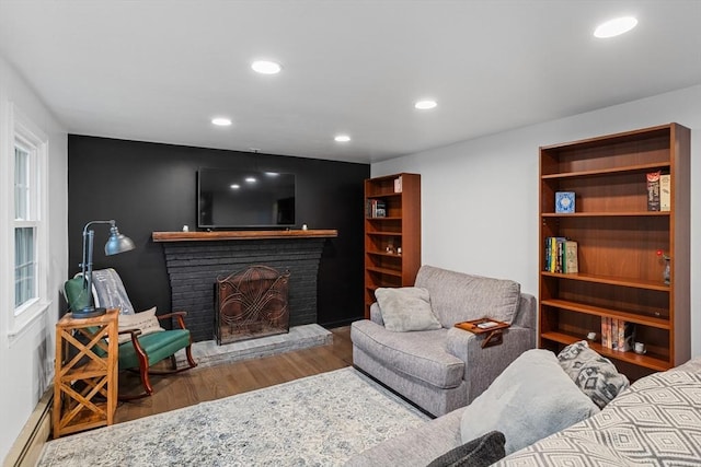 living area with wood finished floors, a fireplace, recessed lighting, and baseboard heating
