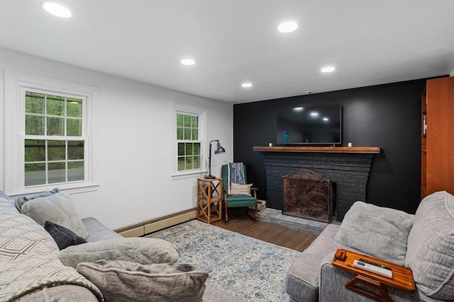 living room featuring a baseboard heating unit, wood finished floors, recessed lighting, and a fireplace