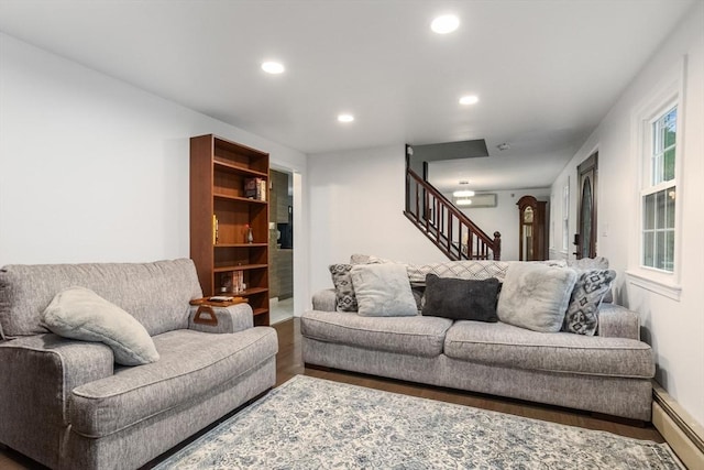 living area featuring baseboard heating, stairway, wood finished floors, recessed lighting, and a wall mounted AC