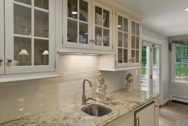 5 Coburn Rd, Hopkinton, MA 01748 - kitchen featuring a sink, glass insert cabinets, decorative backsplash, light stone counters, and wood finished floors