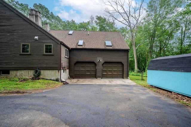 43 Mill Rd, North Andover, MA 01845 - view of side of property with a chimney, driveway, an attached garage, roof with shingles, and a shed