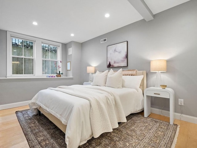 bedroom with hardwood / wood-style floors and beam ceiling