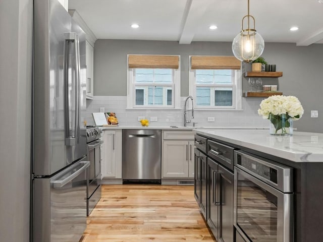 kitchen with light stone counters, decorative backsplash, light hardwood / wood-style floors, and appliances with stainless steel finishes