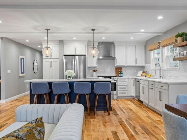 kitchen with wall chimney exhaust hood, sink, pendant lighting, stainless steel appliances, and white cabinets