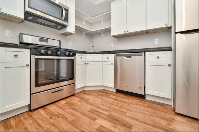 225 Washington, Boston, MA 02121 - kitchen featuring stainless steel appliances, dark countertops, light wood-style flooring, and white cabinetry