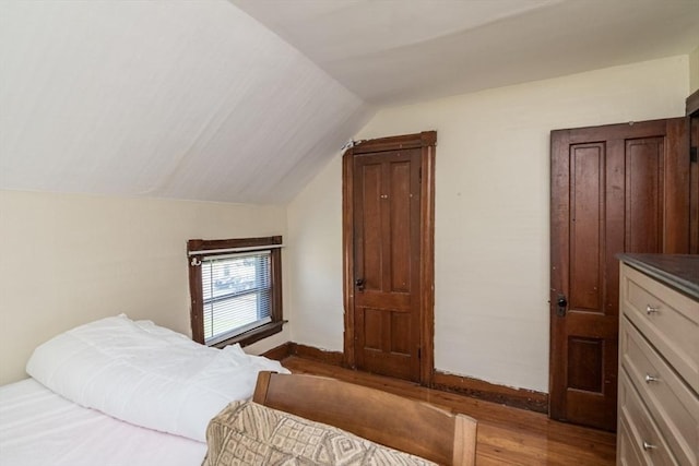 bedroom featuring vaulted ceiling, wood finished floors, and baseboards