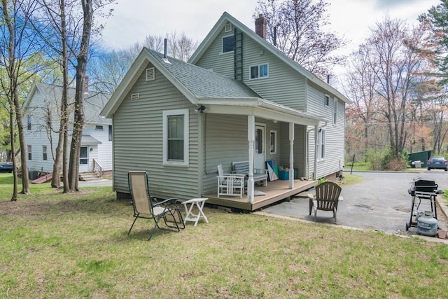 rear view of property featuring a shingled roof, a yard, a chimney, and a deck