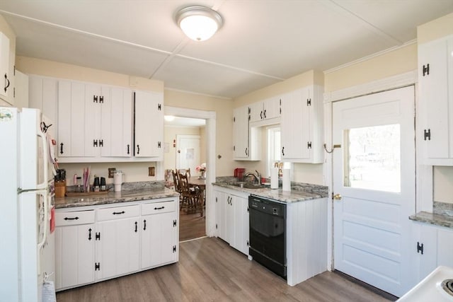 kitchen with freestanding refrigerator, white cabinetry, black dishwasher, and light wood-style floors