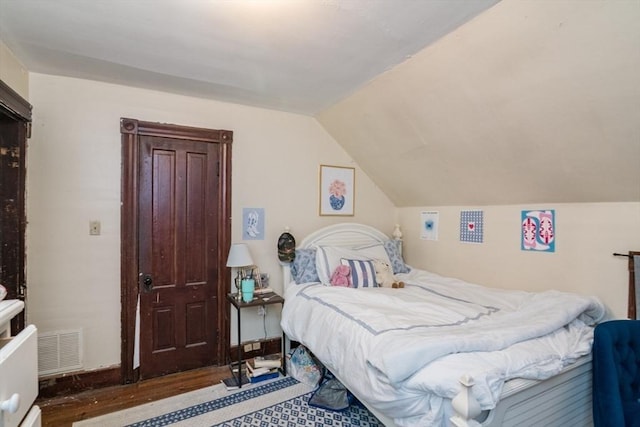 bedroom with visible vents, wood finished floors, and lofted ceiling