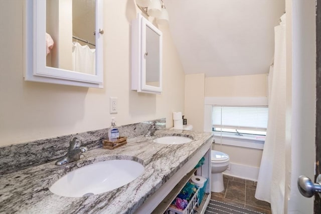 bathroom featuring a sink, double vanity, lofted ceiling, and toilet