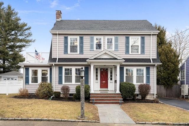 view of front of property featuring a shingled roof, a chimney, fence, and a front yard