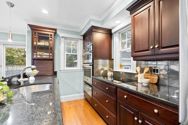 kitchen featuring light wood finished floors, stainless steel appliances, tasteful backsplash, ornamental molding, and a sink