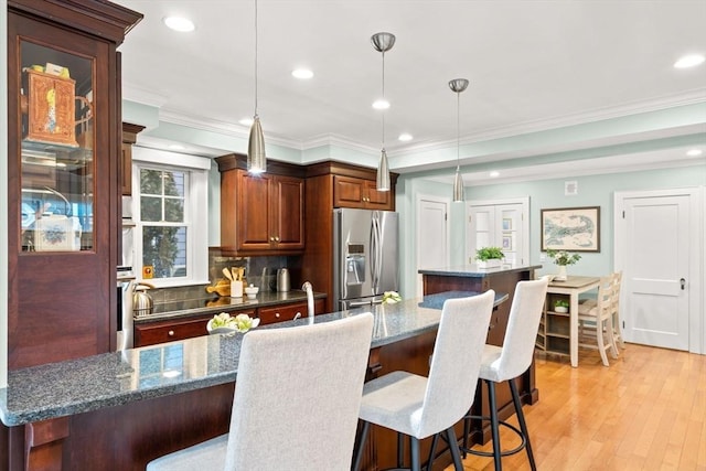 kitchen with stainless steel appliances, a center island, light wood-style floors, and a kitchen bar