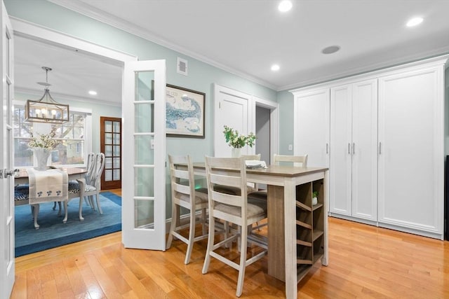 dining area with visible vents, crown molding, french doors, light wood-style floors, and a chandelier