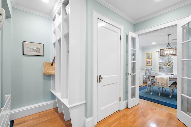 mudroom featuring a notable chandelier, french doors, light wood-style flooring, and crown molding