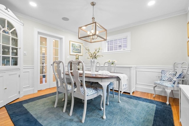 dining room with ornamental molding, wainscoting, and wood finished floors