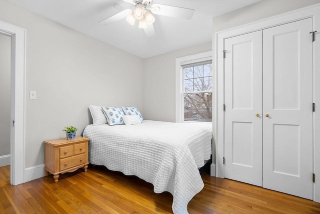 bedroom featuring wood-type flooring, baseboards, ceiling fan, and a closet