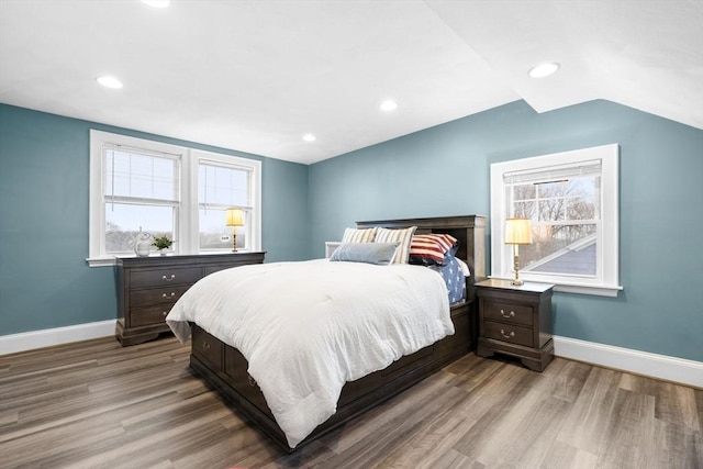 bedroom with vaulted ceiling, wood finished floors, and baseboards