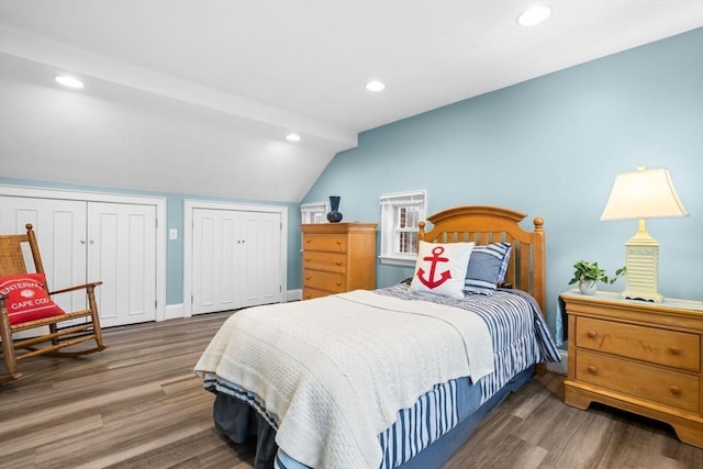 bedroom with lofted ceiling, recessed lighting, wood finished floors, baseboards, and multiple closets