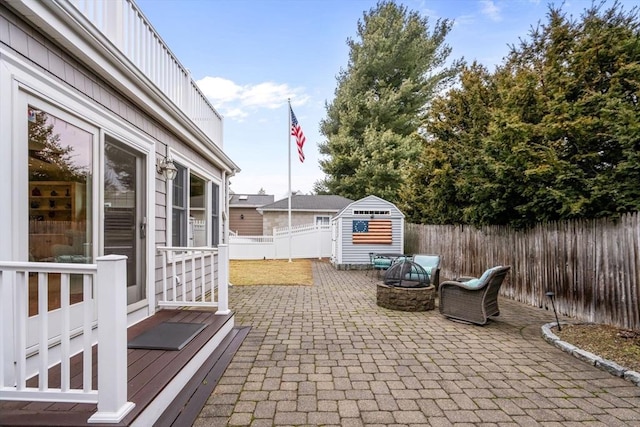 view of patio with a fenced backyard, a storage unit, and an outbuilding