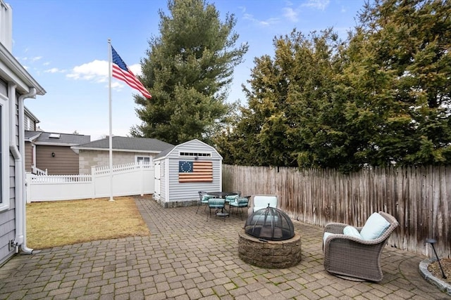 view of patio / terrace featuring a storage shed, a fenced backyard, a fire pit, and an outdoor structure