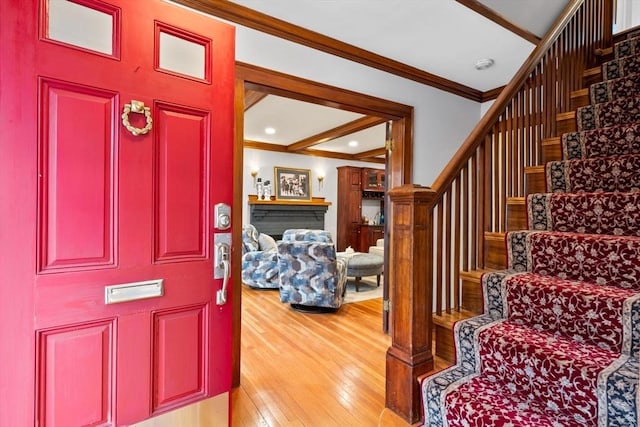 foyer entrance featuring recessed lighting, a fireplace, stairs, wood-type flooring, and crown molding