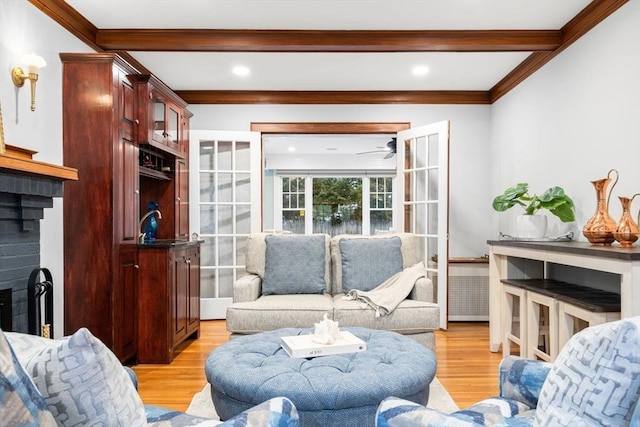 living area featuring light wood finished floors, beamed ceiling, and a fireplace