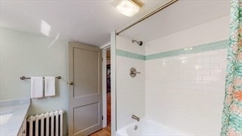 bathroom with shower / bath combo, vanity, and radiator