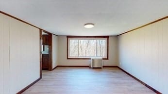 spare room with light wood-type flooring and radiator heating unit