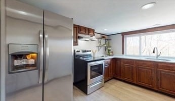 kitchen with appliances with stainless steel finishes, sink, and light hardwood / wood-style flooring