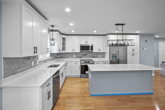 kitchen with hanging light fixtures, white cabinetry, stainless steel appliances, and a kitchen island