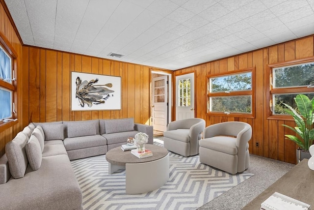 carpeted living room featuring wooden walls