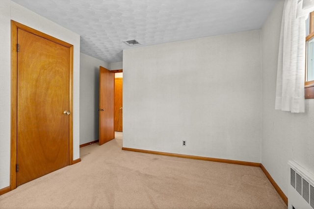 carpeted empty room featuring radiator heating unit