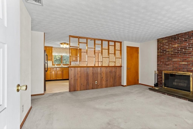 unfurnished living room featuring light colored carpet, a textured ceiling, and a fireplace