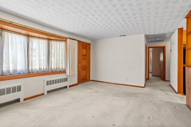 unfurnished room featuring light carpet and radiator heating unit