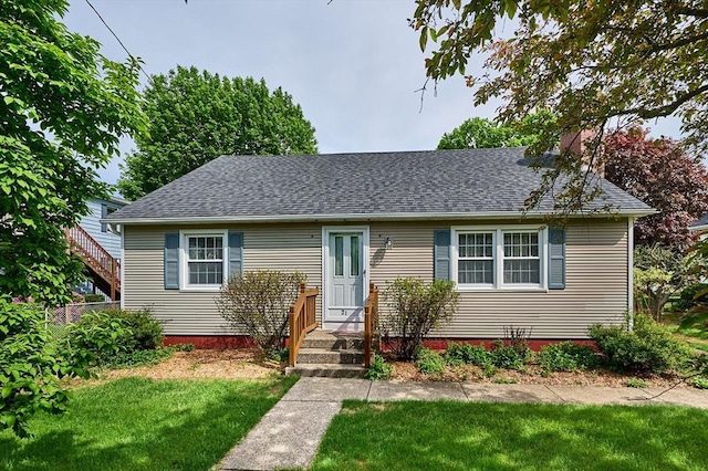 new england style home featuring a front yard and a shingled roof