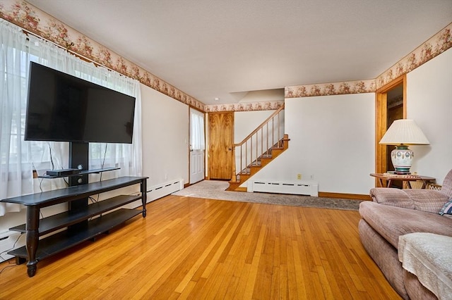 living area featuring baseboard heating, stairway, hardwood / wood-style flooring, and baseboards